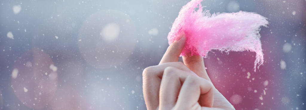 woman holds cotton candy between finger and thumb